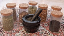 Image of a pestle and mortar surrounded by jars of herbs for healing